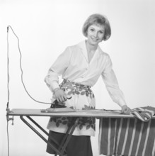 Ironing in the 1960s. A woman seen ironing curtains, smiling at the camera in the photographers