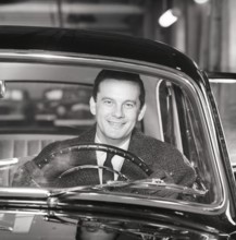 Driving in the 1960s. A man behind the steering wheel in his car looks happy. Sweden 1960.
