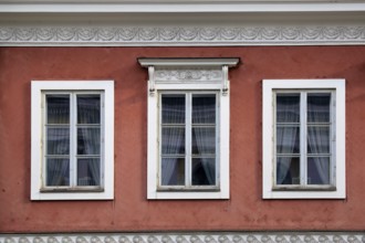 Detail of three windows on the exterior of a red, classic, historic city building in Helsinki,