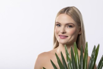 A smiling woman poses with a vibrant tropical plant against a soft light backdrop, showcasing