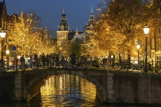Bicycles parked on a night-lit bridge over a canal, Amsterdam, Netherlands