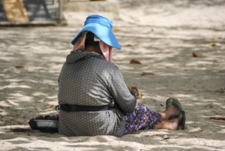 Balinese woman resting quietly on the beach, enjoying the peaceful atmosphere