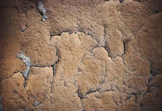 The close-up of peeling layers of plaster and paint on a concrete wall