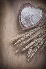 Wooden bowl with flour golden rye wheat ears on wood board
