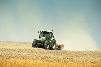 Tractor plowing field on blue sky background