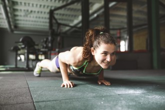 The girl does push-ups from the floor in the gym. Training muscles of the back, arms and press.