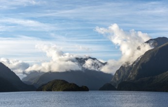 Sun rising over Doubtful Sound, Clouds hanging low on the mountains, South Island of New Zealand