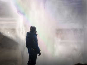 Male tourist in warm clothes standing behind huge majestic Seljalandfoss waterfall in Iceland