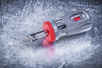 Reversible screwdriver on metallic background construction concept