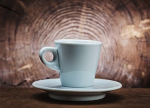 White ceramic coffee cup on vintage wood background with cross cut of tree trunk