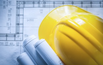 Building helmet rolled construction plans on blueprint