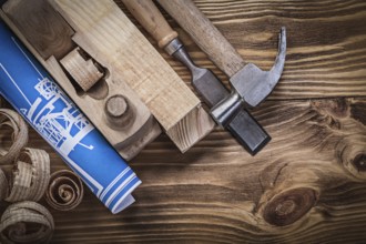 Blue construction plan shaving plane claw hammer chisel wooden studs shavings on wood board