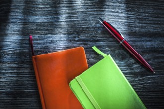Green and orange notebooks on wooden board