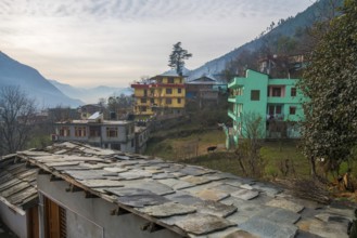A roof made of thin stone plates nailed to a wooden beam and town Kullu. Foggy morning in Himachal