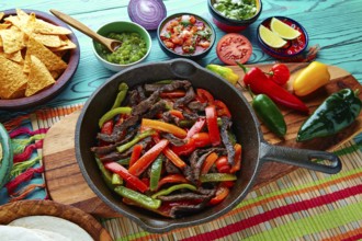 Beef fajitas in a pan with sauces chili and sides Mexican food