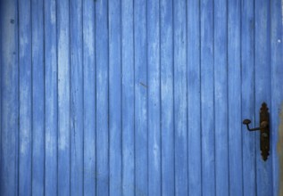 Blue old mediterranean wooden door detail with black handle