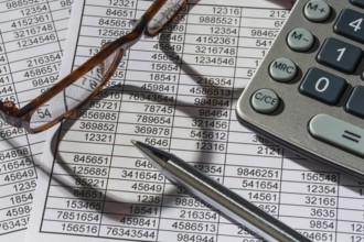 A calculator lies on the figures of a balance sheet and statistics. Symbol photo for turnover,
