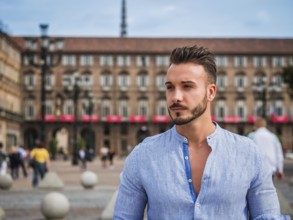 One handsome young man in urban setting in European city, standing, wearing shirt