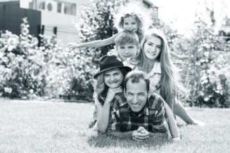Happy family lying on the graß, having weekend in summer park