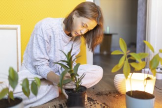 Woman intently plants indoors, surrounded by pots in a cozy setting