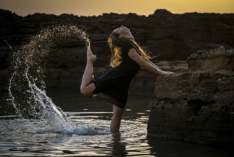 Middle-aged woman dancing and throwing water in the air, Maioris beach, llucmajor, Majorca,