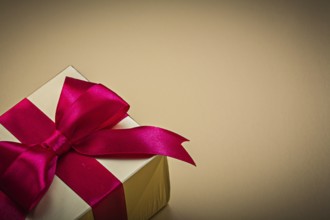 Wrapped present with tied bow on golden background holidays concept