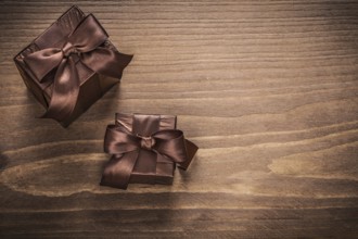 Packed glittery gift containers with bows on vintage wooden board