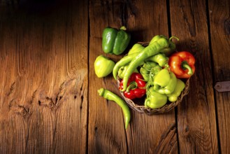 Various harvested peppers and hot peppers in a basket