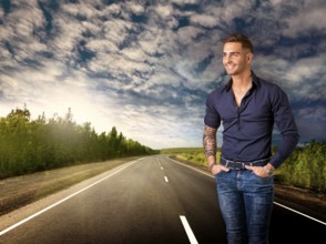 Handsome young man in blue shirt and jeans posing isolated on white background in studio, smiling