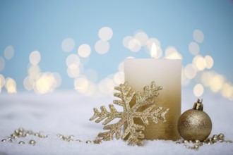 Christmas or new year candle with festive ornaments and bokeh lights on snow, family holidays