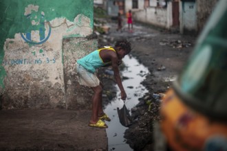Child throwing rubbish into a gutter on the street, environmental pollution, poverty Kinshasa,