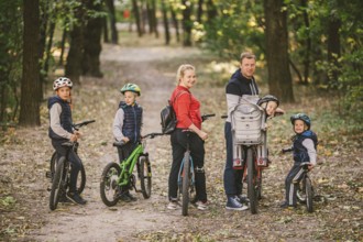 Parents and kids cycling on forest trail. family in warm clothes cycling autumn park. Family