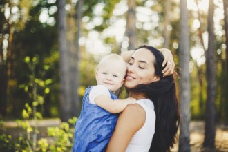 Young beautiful fashionable mother with long brunette hair holding a daughter's blonde with blue