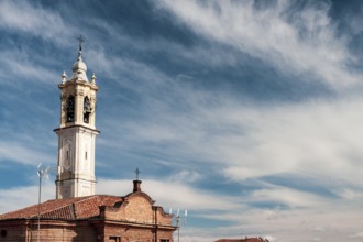 Historic church bell tower reaching out to a clear blue sky adorned with delicate clouds. Vigevano,
