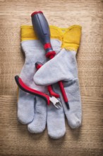 Little nippers screwdriver and protective working glove on wooden board construction concept