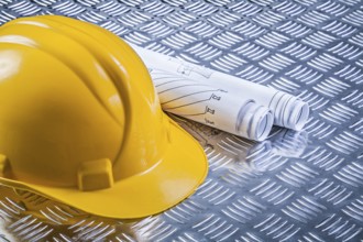 Blueprint rolls hard hat on corrugated metal plate construction concept