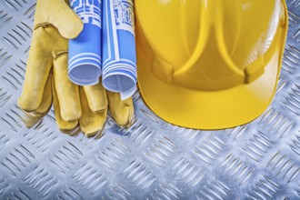 Blue engineering drawings hard hat safety gloves on corrugated metal background construction