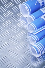 Blue rolled up construction drawings on fluted metal background vertical view