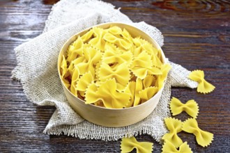 Farfalle pasta in bark box on burlap on the background of dark boards