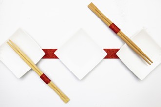 Ceramic bowls and bamboo chopsticks for sushi food with red and white decoration
