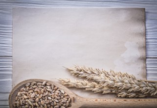 Wheat rye ears corn wooden spoon vintage paper on wood board food and drink concept