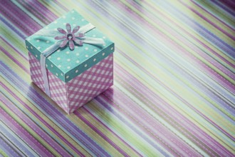 Wrapped gift box on stripy fabric background celebrations concept