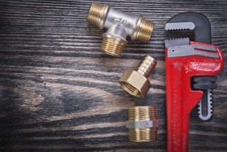 Set of monkey wrench brass equal tee nipple hose connector on wooden board plumbing concept
