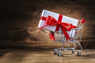 White giftbox in shopping cart on vintage wood