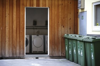 Washing machines next to each other in a storage room in the backyard of an apartment block