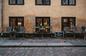 Outdoor cafe seating on cobblestone street with warm lighting and a rustic atmosphere in central