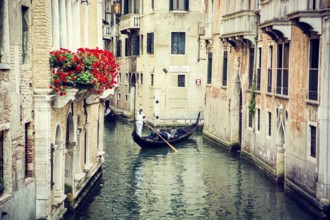 Typical canal in Venice, Italy with traditional gondola in the distance