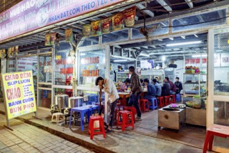 A street restaurant at night with diners at tables and vibrant neon lights, restaurant in the