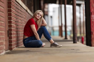 A beautiful blonde woman poses joyfully for the camera, showcasing her stylish spring clothing.