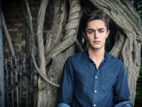 One handsome blue eyed young man in urban setting in European city park